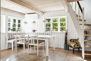 a dining room with a white table and chairs at Timber-Framed With Bright And Idyllic Garden in Juelsminde