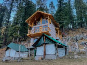 a tree house with a balcony on top of it at Singing Woods Kutla in Kulu