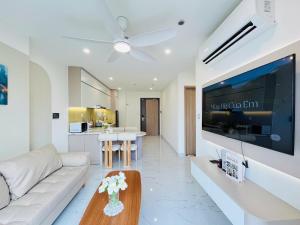 un salon avec un canapé blanc et une grande télévision dans l'établissement May Homes - 3PN BS8 Tropiacal Vinhomes Grand Park, à Long Bình