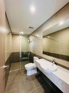 une salle de bain avec toilettes, lavabo et miroir dans l'établissement May Homes - 3PN BS8 Tropiacal Vinhomes Grand Park, à Long Bình