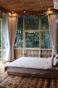 a bed in a room with a large window at Dinh Gia Trang - Homestay & Coffee in Yên Bái
