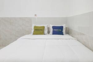 a white bed with two pillows on top of it at Urbanview Aurel House Cirebon in Plered