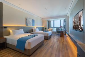 una camera d'albergo con due letti e una televisione di 青岛西海岸城市阳台Madison酒店 a Qingdao