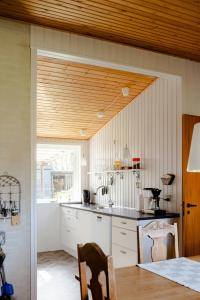 cocina con armarios blancos y techo de madera en Authentic Family Summer House At The Limfjord, en Roslev