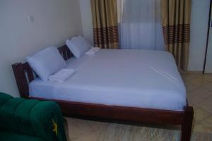a bed with white sheets and blue pillows in a room at Classic Studio Bamburi in Mombasa