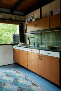 - une cuisine avec des placards en bois, un évier et un tapis dans l'établissement 60S Cabin With Vintage Finds And Wild Surroundings, à Tjørneholm