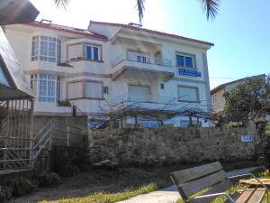 duży biały budynek za kamienną ścianą w obiekcie Hostal Santa Marta Playa w mieście Baiona