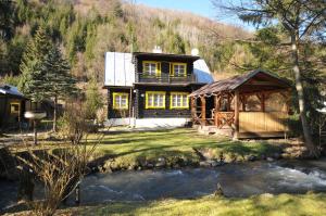 a house on a hill with a creek in front of it at Chata Lieska in Horná Lehota