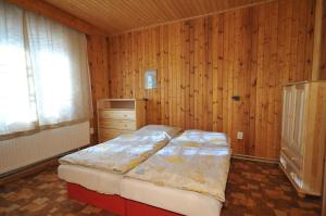 Chata Lieska في Horná Lehota: غرفة نوم بسرير وجدار خشبي