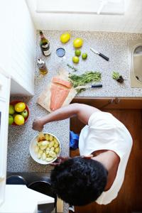 a man standing in a kitchen preparing food on a counter at The Nooq Alvik - Hotel & Studios in Stockholm