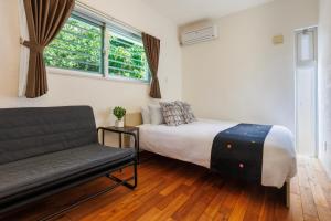 een slaapkamer met een bed, een bank en een raam bij 美ら海水族館まで車で5分 広い庭 最大10名 まるまる貸し切り 花の雲 in Motobu
