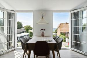 a dining room with a table and chairs and large windows at Enjoy Møn From Historic House in Stege