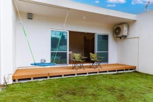 een terras met twee stoelen en een tafel op een huis bij 美ら海水族館まで車で5分 広い庭 最大10名 まるまる貸し切り 花の雲 in Motobu