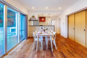 een keuken en eetkamer met een tafel en stoelen bij 美ら海水族館まで車で5分 広い庭 最大10名 まるまる貸し切り 花の雲 in Motobu