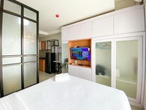 Un dormitorio con una cama blanca y un televisor. en Best Choice and Modern Studio at Mataram City Apartment By Travelio, en Kejayan 8 fotos más