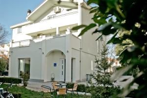 a white building with chairs and tables in front of it at Casa Verde in Međugorje