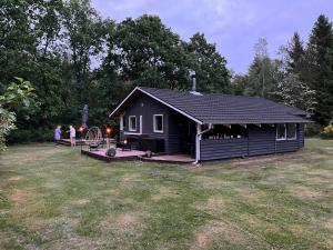 海宁Peaceful Home Surrounded By Fields And Forest的一间黑色小屋，外面站着一些人