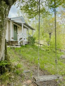 una casa con un columpio delante de un árbol en Delight For The Soul In Österlen's Nature, en Gärsnäs