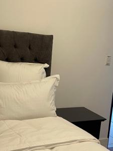 Una cama con sábanas y almohadas blancas y una mesa. en Desert Pearl, en Windhoek