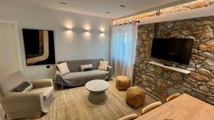 a living room with a stone wall with a tv at Aeolian apartment in Mytilini +5 photos