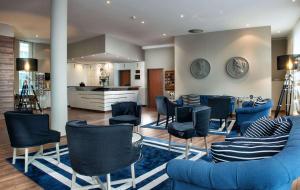 a living room with blue chairs and a kitchen at Sunday Hotel and Spa Wismar in Wismar