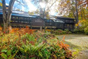 a building with a sign in the middle of a garden at Hotel Wohnen in Hakuba