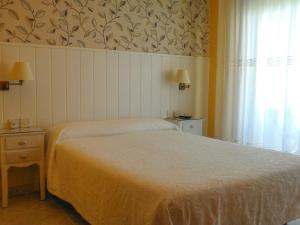 a bedroom with a white bed and a window at Hostal Santa Marta Playa in Baiona