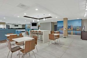 an office lobby with tables and chairs and a bar at Clarion Pointe Near Erie Casino in Erie