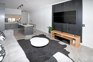 a living room with a couch and a tv at Thango Res Ellipse Waterfall. in Midrand