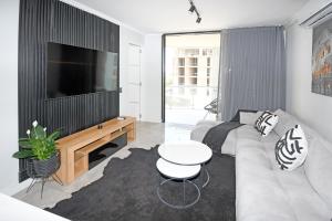 a living room with a couch and a flat screen tv at Thango Res Ellipse Waterfall. in Midrand