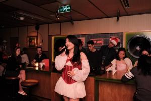 a woman standing at a bar singing into a microphone at CLASSYC Hotel in Hanoi