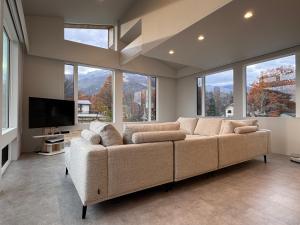 長野市にあるMK Hakuba, Great Mountain Viewsの大きなソファと窓付きの広いリビングルームが備わります。