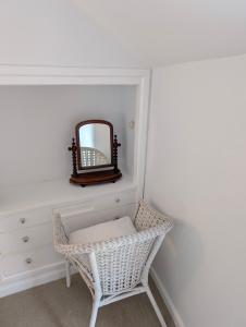 a dressing room with a wicker chair and a mirror at Cosy Beach Cottage - Cawsand in Cawsand