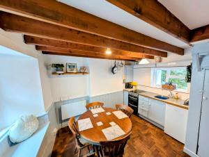 a kitchen with a wooden table and chairs in a room at Cosy Beach Cottage - Cawsand in Cawsand