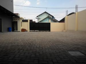 a brick parking lot with a fence and a house at deKOST Madiun in Madiun +8 photos