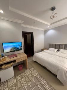 a bedroom with a bed and a desk with a television at Smart Entry Room Grnada in Riyadh