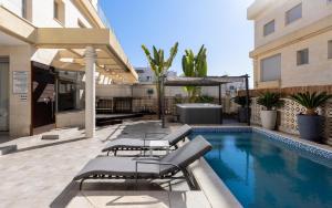 埃拉特Sahara - Designed Duplex with a private pool的建筑物旁边有带躺椅的游泳池