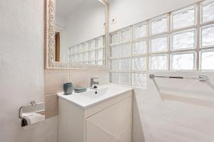 ein weißes Badezimmer mit Waschbecken und Spiegel in der Unterkunft Acogedor estudio en Pedregalejo junto al mar in Málaga + 22 Fotos