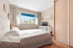 ein Schlafzimmer mit einem weißen Bett und einem Fenster in der Unterkunft Acogedor estudio en Pedregalejo junto al mar in Málaga