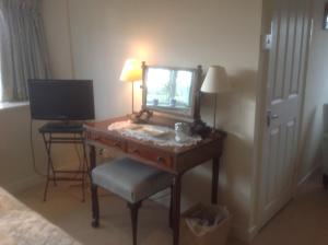 einen Schreibtisch mit einem Spiegel und einem Stuhl in einem Zimmer in der Unterkunft The Coach House in Ross on Wye