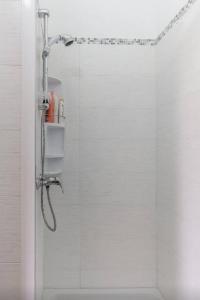 a shower in a bathroom with white tiles at Il Paesino Loft in Licodia Eubea