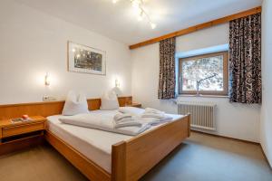 una camera da letto con un letto con lenzuola bianche e una finestra di Apartmenthaus Beaverwier a Biberwier