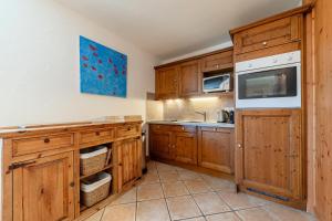 uma cozinha com armários de madeira e uma pia em Résidence Bergerie Des 3 Vallees F - Appartement 4 pièces 6 personnes situé dans le charmant village des allues MAE-4991 em Les Allues mais 8 fotografias