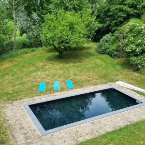 a swimming pool with two blue chairs in a yard at Le Moulin de mon Père, 20 pers, Piscine, campagne. in Dompierre-sur-Nièvre