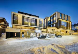 a building with cars parked in a parking lot at Grand Hotel Hradec in Pec pod Sněžkou