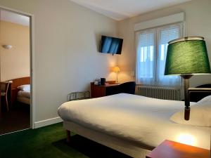 a hotel room with a large bed and a window at Logis Hôtel & Restaurant - Le Saint-Louis in La Suze-sur-Sarthe