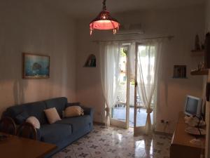 een woonkamer met een blauwe bank en een glazen schuifdeur bij Santa Caterina in Ischia