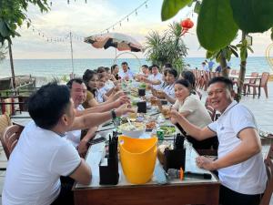 a group of people sitting at a table eating food at Newlife Homestay & Restaurant in Dong Hoi