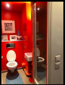 a red bathroom with a toilet and a sink at Superbe loft avec terrasse et jacuzzi aux Lilas près de Paris in Les Lilas
