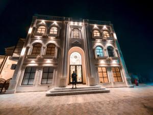 a man standing in front of a building at night at Grand Shalimar Hotel in Multan